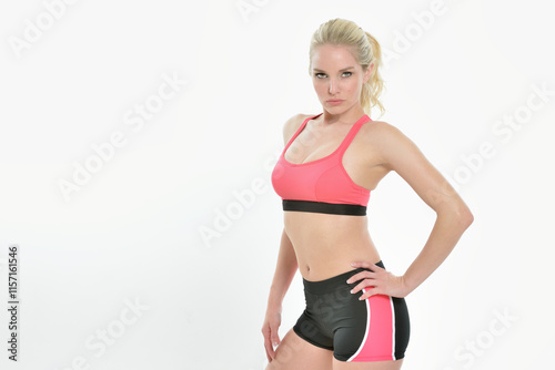 Sexy young Caucasian woman - fitness model - posing in lycra shorts and sports bra - sultry