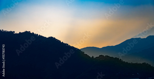 Evening blue lake waters reflect the multiple layers of mountains. Golden-yellow orange light glowing on the mountain tops adds a magical touch to the scenery of Tehri Lake. photo