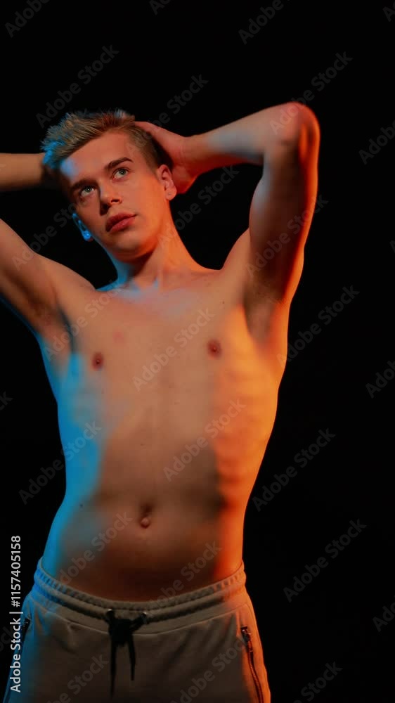 Young man model posing in the dark with red and blue light in the studio Young man model posing in the dark with red and blue light in the studio
