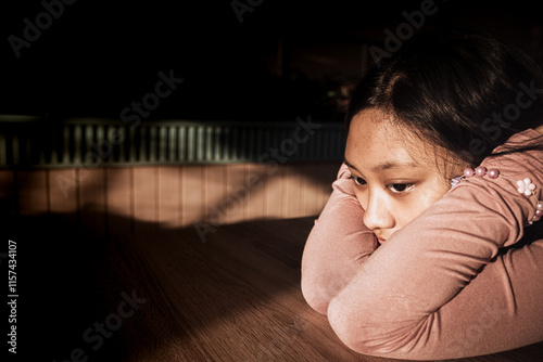 Indonesian Teenage Girl with Sad Expression on Her Face and Her Arms on Table