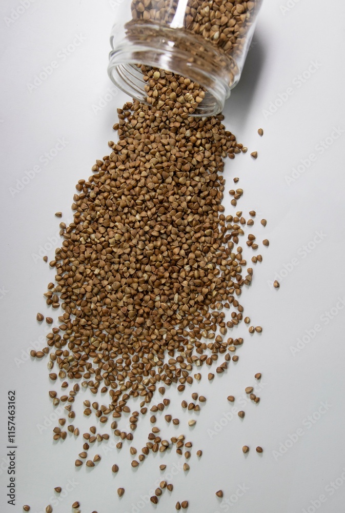 buckwheat on a white background poured out of a transparent jar buckwheat on a white background poured out of a transparent jar