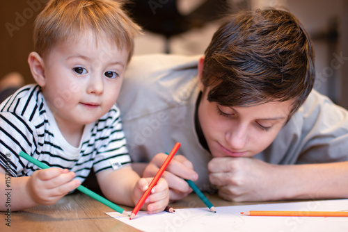 Wallpaper Mural Two children draw with colored pencils. A teenager and a younger brother draw while lying Torontodigital.ca