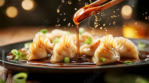 A plate of dumplings is shown with soy sauce being drizzled on top.  photo