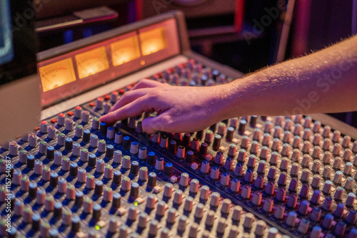 hand adjusting knobs on a sound mixer in a professional recording studio