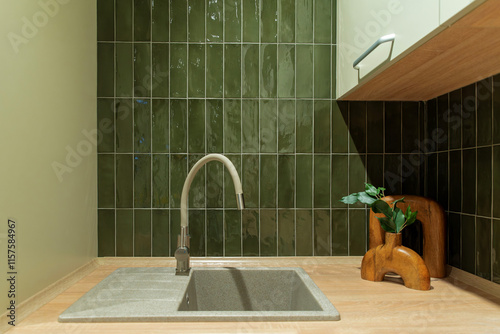 Textured sink paired with a beige faucet and glossy green tiles © Sergey