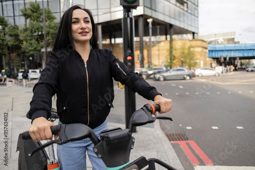 Photography Young woman riding a bike sharing in london city center
