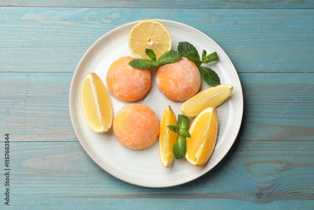 Plate with tasty mochi, cut orange, lemon and mint on light blue wooden table, top view Plate with tasty mochi, cut orange, lemon and mint on light blue wooden table, top view