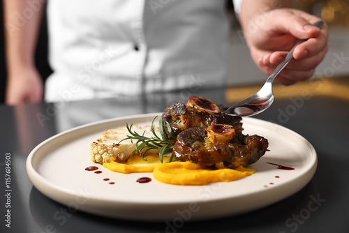 Fotografi Professional chef adding sauce to delicious dish at table indoors, closeup