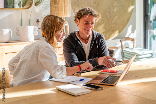 Couple Collaborating at Home with Laptop and Notebooks photo