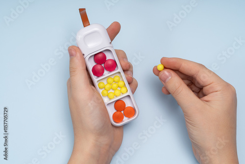 Anonymous person holding a pill box with colorful pills