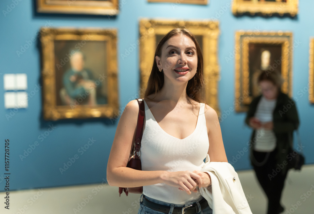 Young woman walks around museum hall, examines showpiece painting and icons at exhibition. Exposition, admire works of Renaissance artists, stand in front of painting, looks at it for long time Young woman walks around museum hall, examines showpiece painting and icons at exhibition. Exposition, admire works of Renaissance artists, stand in front of painting, looks at it for long time