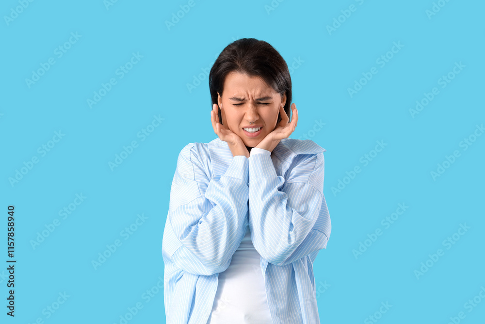 Young girl with otitis feeling pain in ears on blue background Young girl with otitis feeling pain in ears on blue background