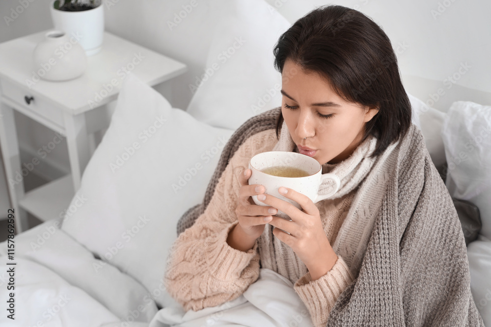 Sick young woman drinking hot tea in bed Sick young woman drinking hot tea in bed