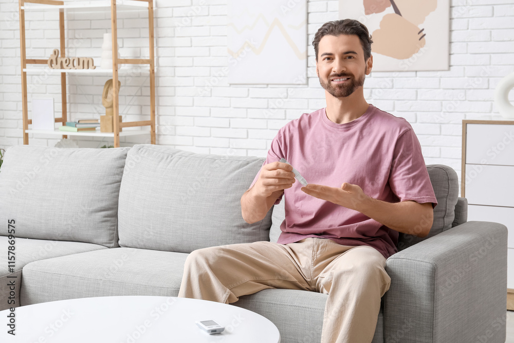 Diabetic young man using lancet pen on sofa at home Diabetic young man using lancet pen on sofa at home