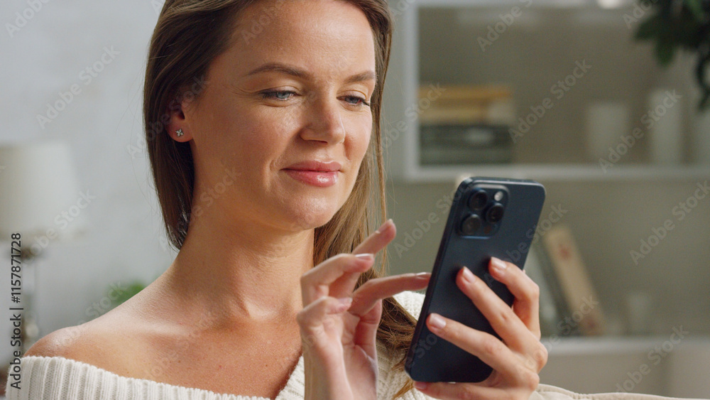 Happy young woman relaxing on a comfortable sofa at home, using her smartphone to browse the internet, read news, chat with friends, and shop online Happy young woman relaxing on a comfortable sofa at home, using her smartphone to browse the internet, read news, chat with friends, and shop online