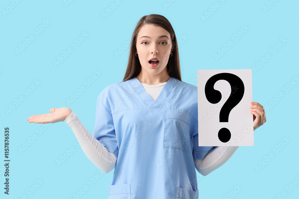 Shocked female doctor with paper question mark on blue background Shocked female doctor with paper question mark on blue background