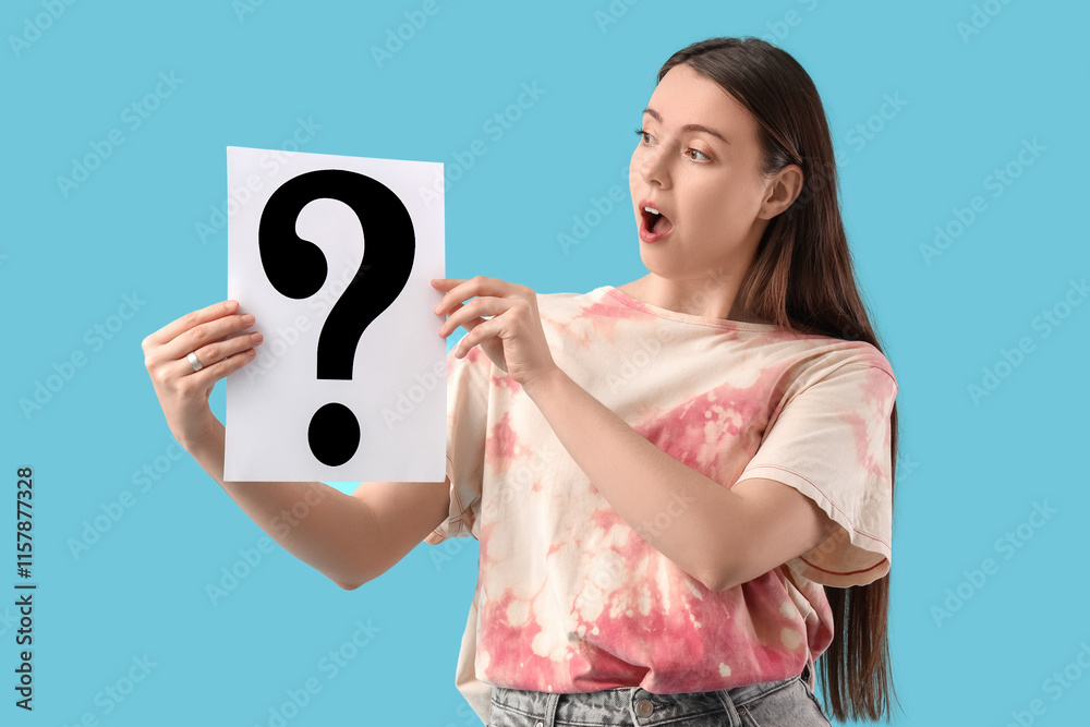 Shocked young woman with paper question mark on blue background Shocked young woman with paper question mark on blue background