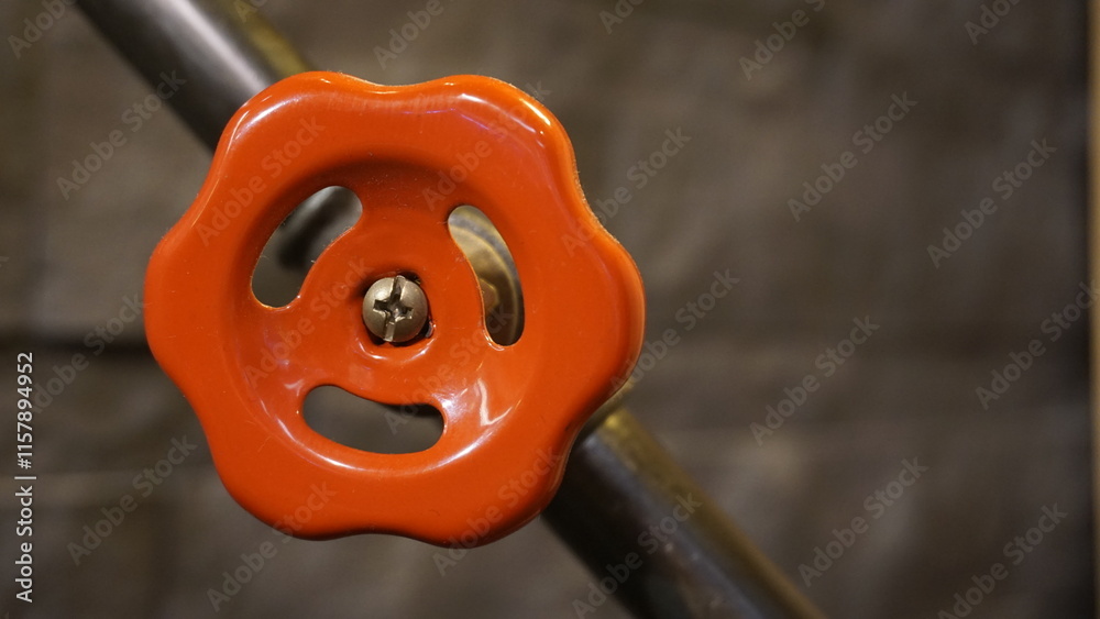 Vibrant orange valve handle standing out against a blurred, neutral background, representing industrial design with a bold touch. Vibrant orange valve handle standing out against a blurred, neutral background, representing industrial design with a bold touch.