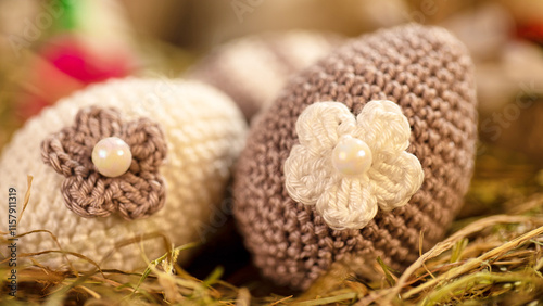 Fotografie A pair of beautifully crafted crochet eggs with flowers and pearl centers, set amidst straw, adding a touch of whimsy and elegance to seasonal decorations