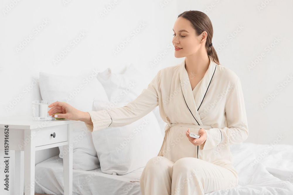 Young pregnant woman with gestational diabetes and glucometer taking lancet pen from table in bedroom Young pregnant woman with gestational diabetes and glucometer taking lancet pen from table in bedroom