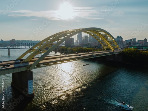 Golden hour view of the city bridge over the river. Cars travel across the bridge as boats navigate the water. Daniel Carter Beard Bridge, Cincinnati, Ohio, United States photo