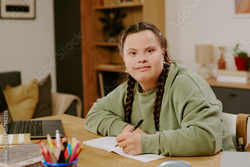 Photos Medium portrait of confident young woman with disability sitting at wooden desk