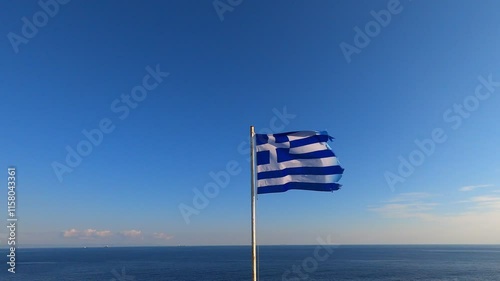 Greek flag waving in slow motion with the sea on the background in Greece