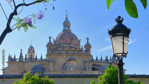 TView of the historic Cathedral of San Salvador dome in Jerez de la Frontera, Spain, with a classic streetlamp and lush greenery under a bright blue sky. photo