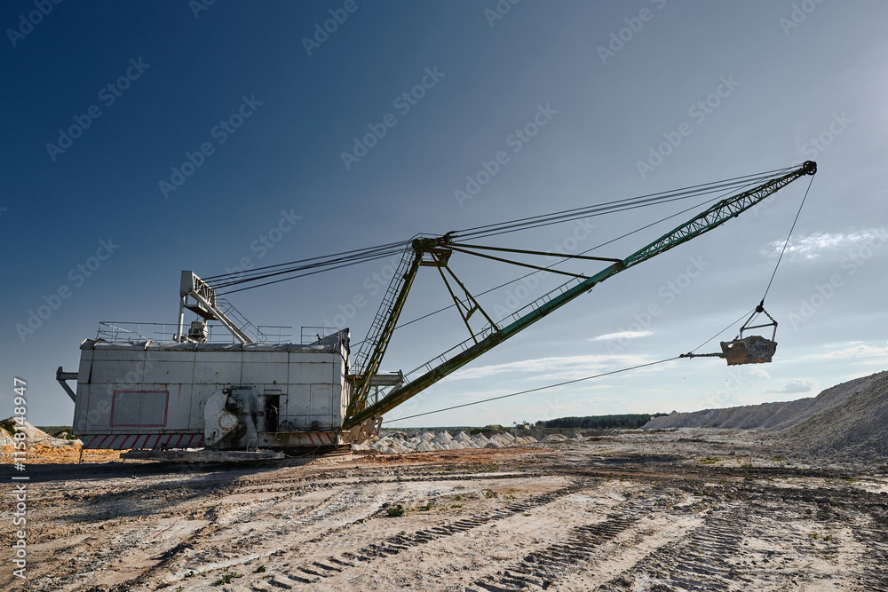 Walking excavator mines chalk in large pit on sunny day Walking excavator mines chalk in large pit on sunny day