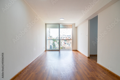 Vista de sala de departamento con amplia mampara con vista a la calle , con acabados modernosm, piso de madera y paredes blancas 