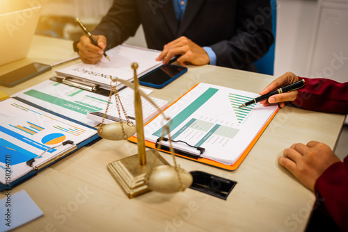 Two male and female lawyers sit at a table in an office, discussing legal matters related to opening a company.They focus on laws, regulations,and collaboration between in-house and business lawyers