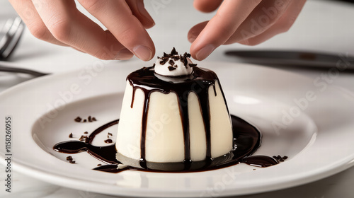 Delicate hands adding final touch of cho te sauce to creamy dessert, enhancing its visual appeal and flavor. This moment captures artistry of dessert preparation