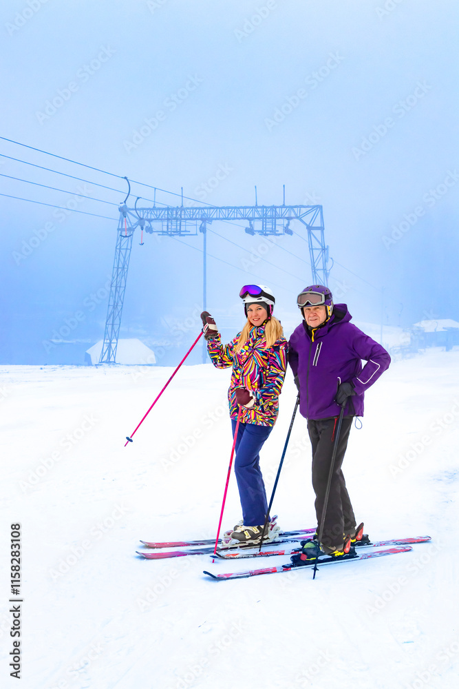 Two father and daughter skiers enjoying a beautiful day on the slopes surrounded by nature and snow