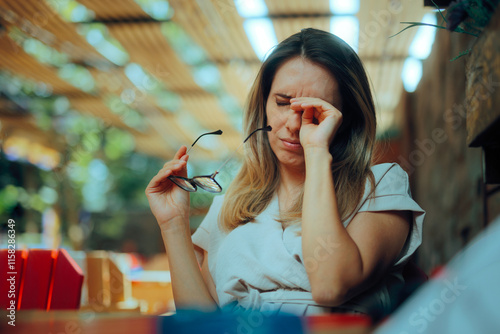 Tired Woman Taking off Glasses Rubbing her Eyes. Stressed lady feeling her eyes itching being irritated 
