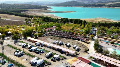Aerial view of a beautiful camping area with caravans and a blue lagoon behind.