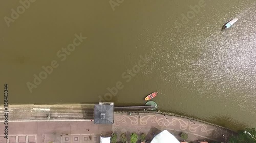 2 boats crossing in a canal in Kuching, with murky waters beneath.