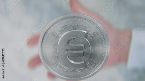 A hand flips a coin marked Dollar and Euro, spinning toward the camera in slow motion photo