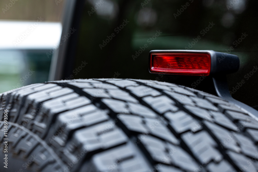 Deep tread of a new off road tire mounted on the rear door of an off-road vehicle. The photo was taken during the day.