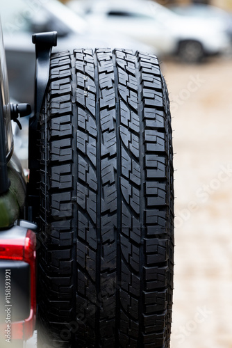Obraz na płótnie Deep tread of a new off road tire mounted on the rear door of an off-road vehicle. The photo was taken during the day. w salonie