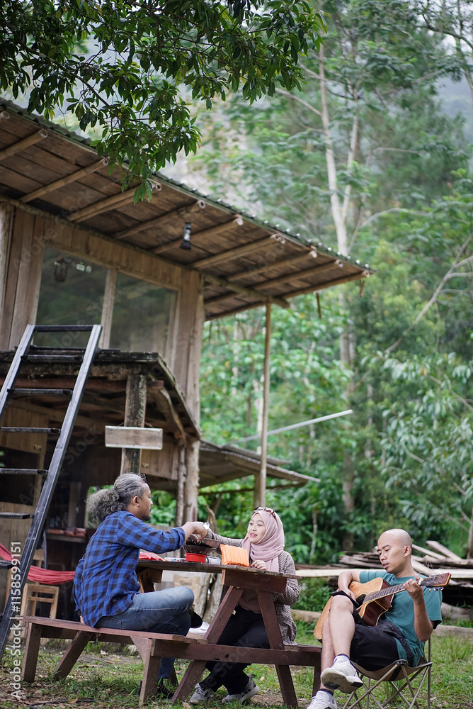 Indonesian men and women in hijab relaxing in front of a forest cabin and frying frozen food, staying in a forest cabin, travel concept. Indonesian men and women in hijab relaxing in front of a forest cabin and frying frozen food, staying in a forest cabin, travel concept.