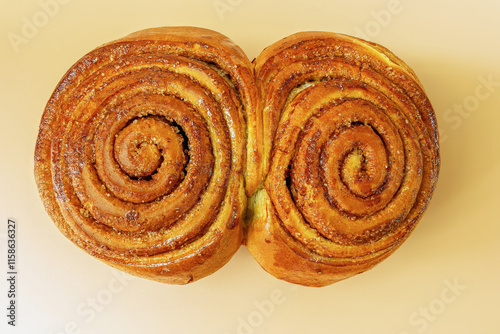 Two cinnamon buns covered with sugar on an orange background