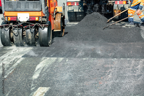 Obraz na płótnie Road workers expertly laying new asphalt on a sunny day in an urban area w salonie