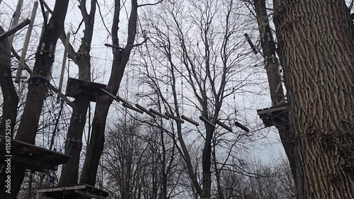 Suspended obstacle course in the park on the trees. Boards on ropes in the air. attraction. Cold