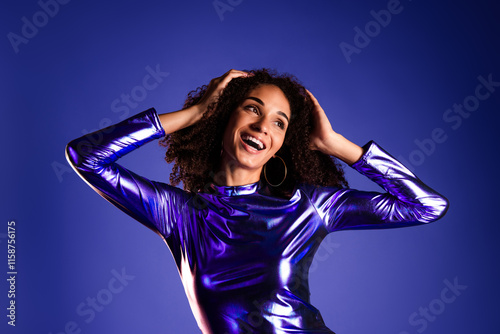 Glamorous young woman in a shimmering dress celebrating against a vibrant purple background photo