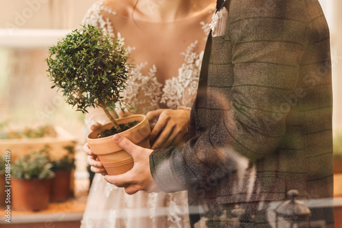 Foto Wedding couple holding a small potted tree in their hands.