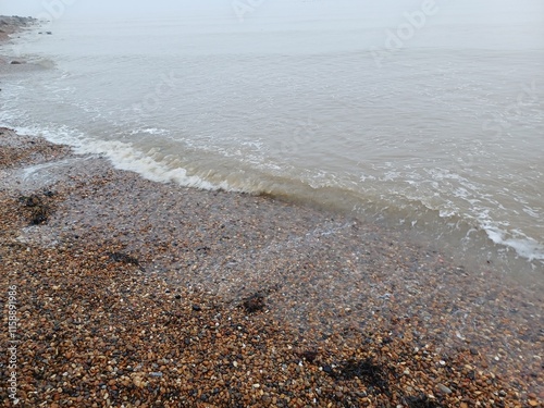 The sea and a shingle beach with the tide coming in waves photo