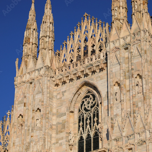 facade of the Milan Cathedral with spires and statues in Gothic style