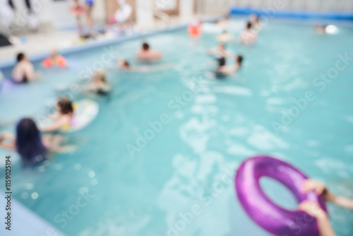 A close-up of a lilac inflatable ring floating in a pool, against a background of blurred people. With space to copy. High quality photo