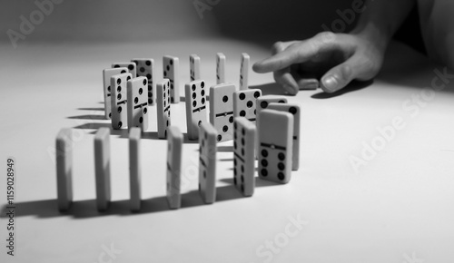 domino game. dominoes are placed on the field and a hand is preparing to push them