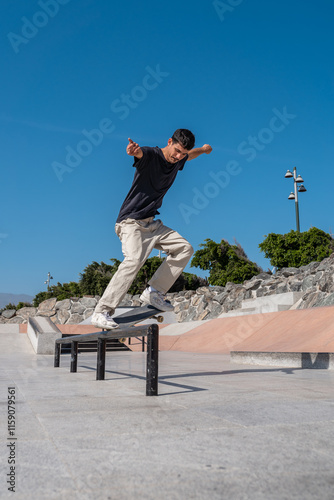 young skater wearing black tshirt does a trick in a skate park rail.